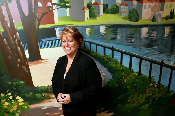 Homeowner Pauline Harris poses for a portrait beside a mural in her kitchen - Arianne Teeple