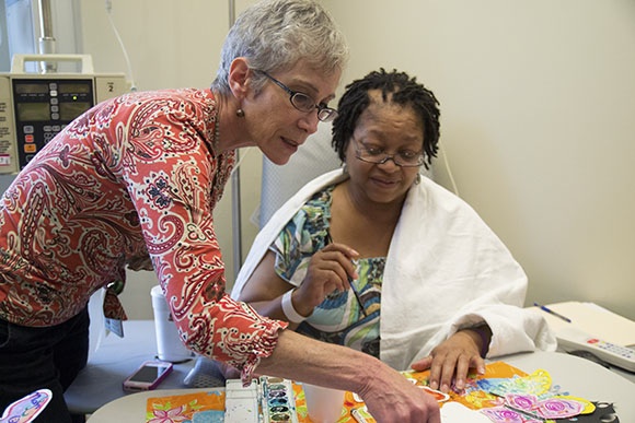 Mercy Medical Center volunteer Andrea Cooper assists Eulalia M. Bell with her art project   